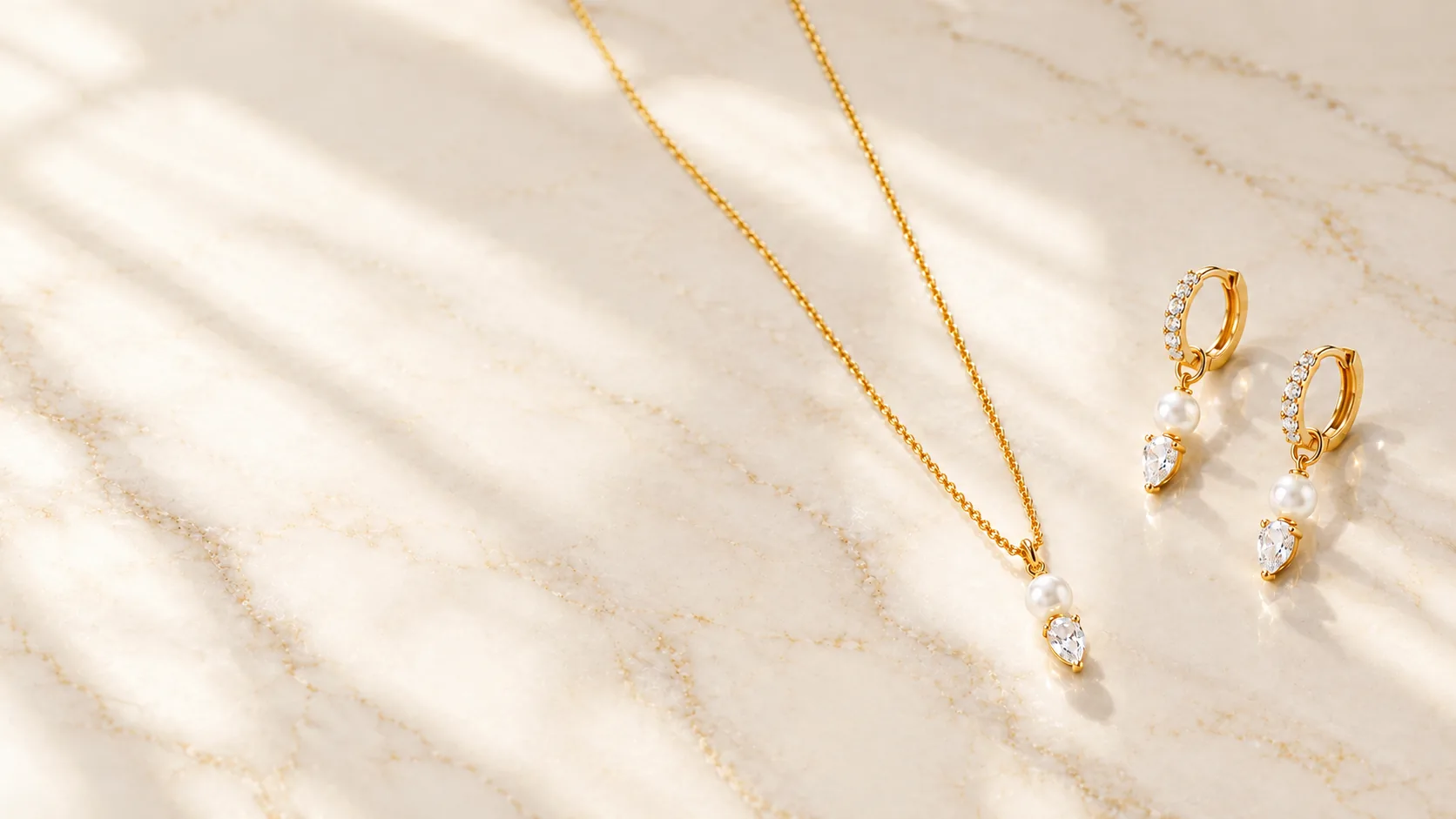 Collar y pendientes en plata de ley 925 con baño de oro, perla y circonita sobre mármol